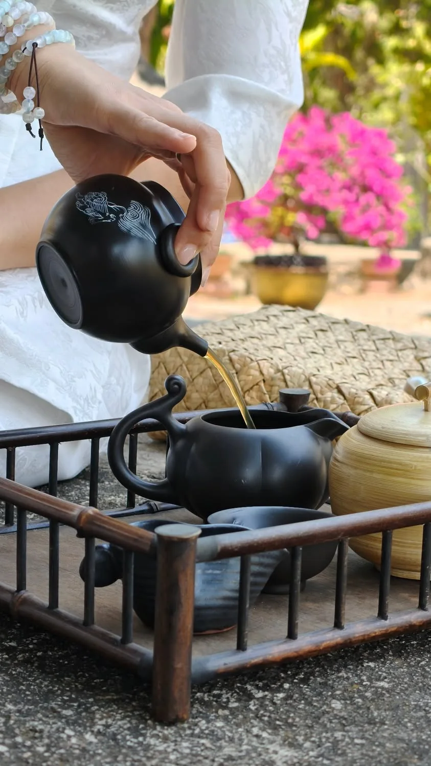 Bàn tay rót trà từ ấm đất