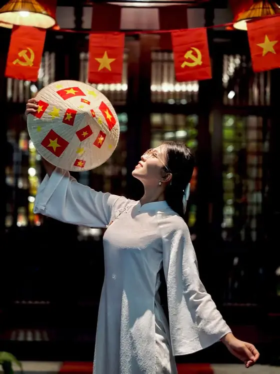 Vy Đan áo dài trắng nâng chiếc nón lá dán cờ đỏ sao vàng