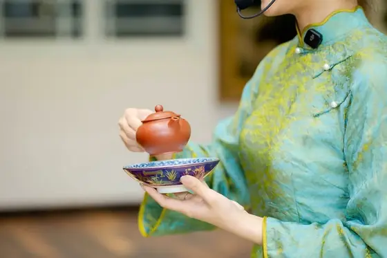 Đôi tay nâng ấm tử sa trong tà áo xanh ngọc